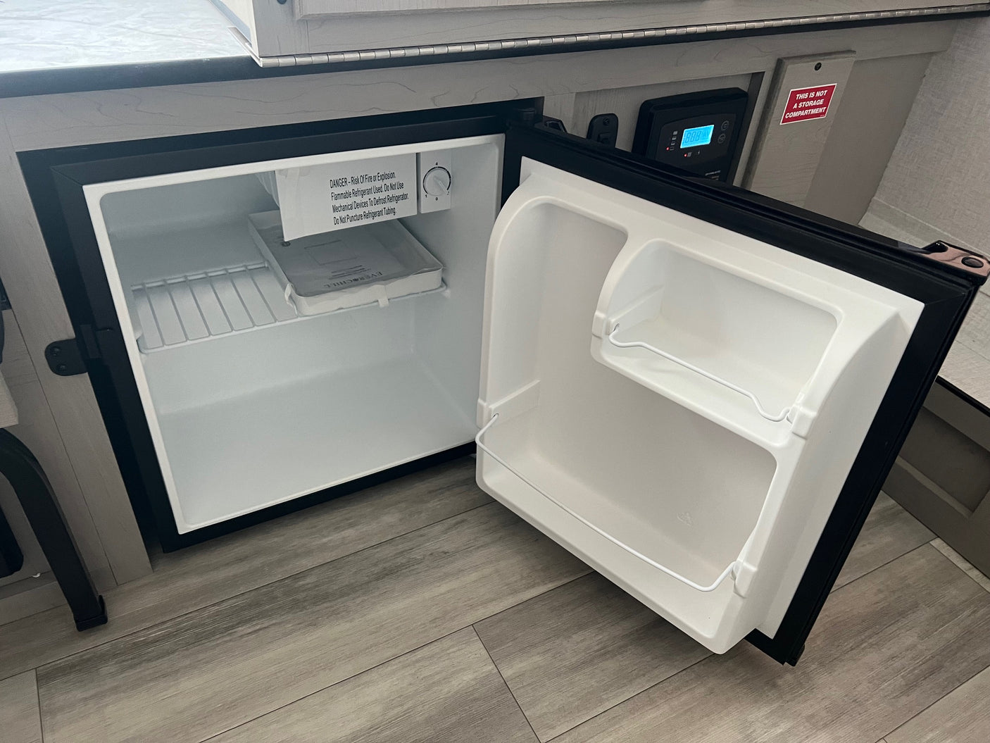 Inside an RV, an open Everchill mini-fridge reveals its thermostat and safety warnings, perfect for an rv rental.