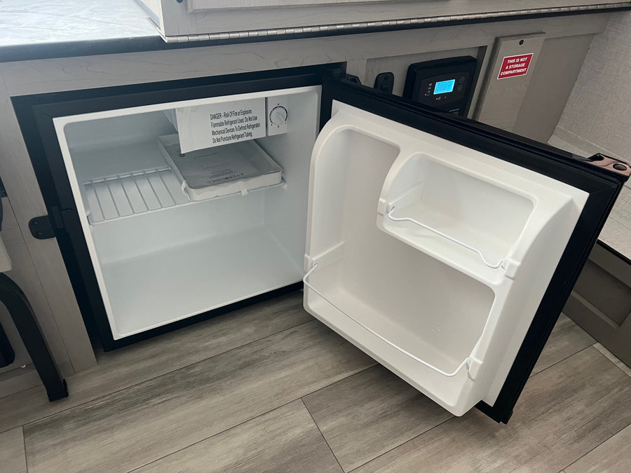 Inside an RV, an open Everchill mini-fridge reveals its thermostat and safety warnings, perfect for an rv rental.