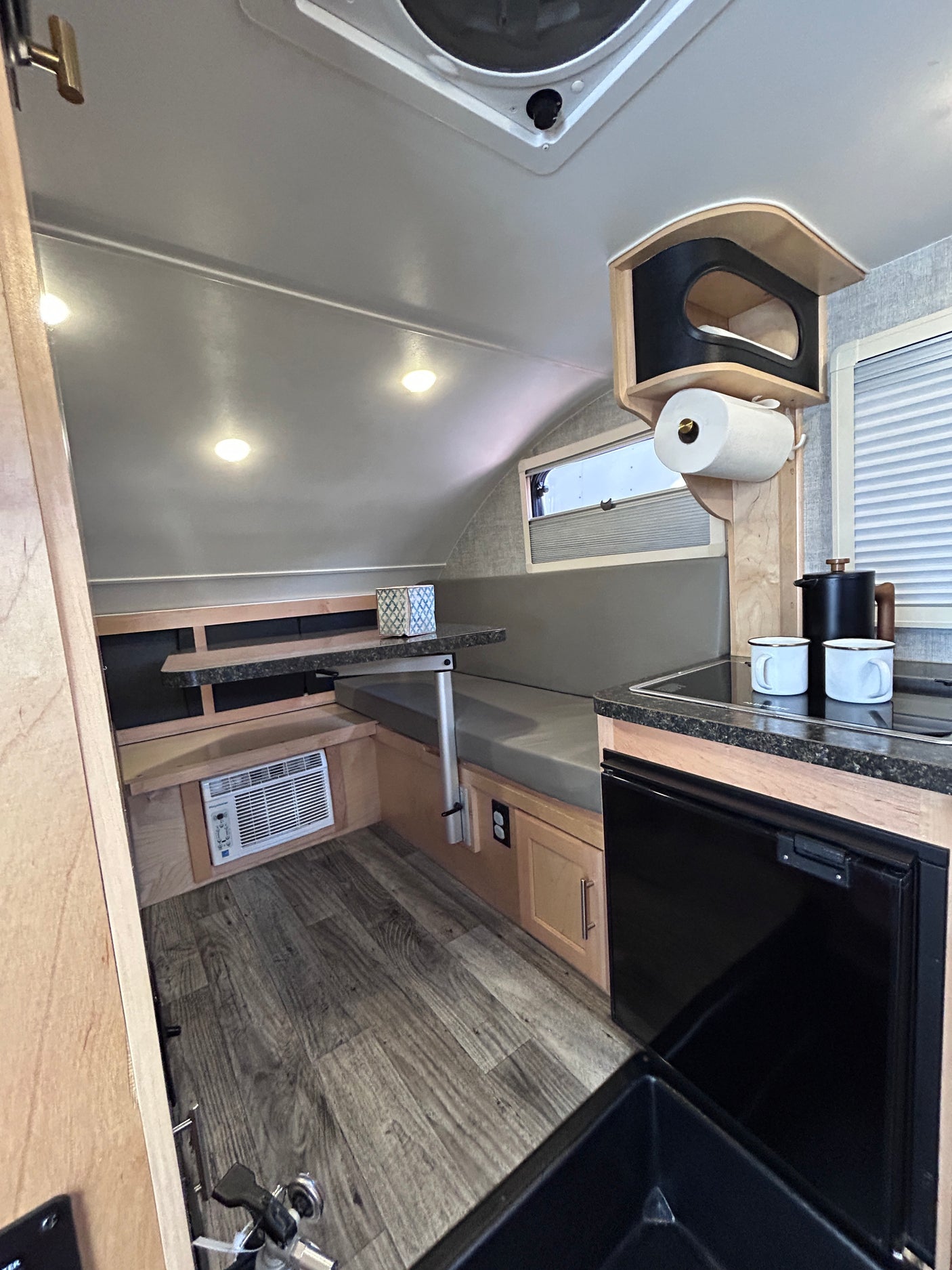 RV rental interior features a compact dinette, kitchenette with sink & fridge, plus AC. Ideal for cozy adventures.