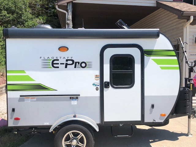 A compact, modern Flagstaff E-Pro travel trailer in white/gray with green trim, parked outside. Perfect for an rv rental adventure!