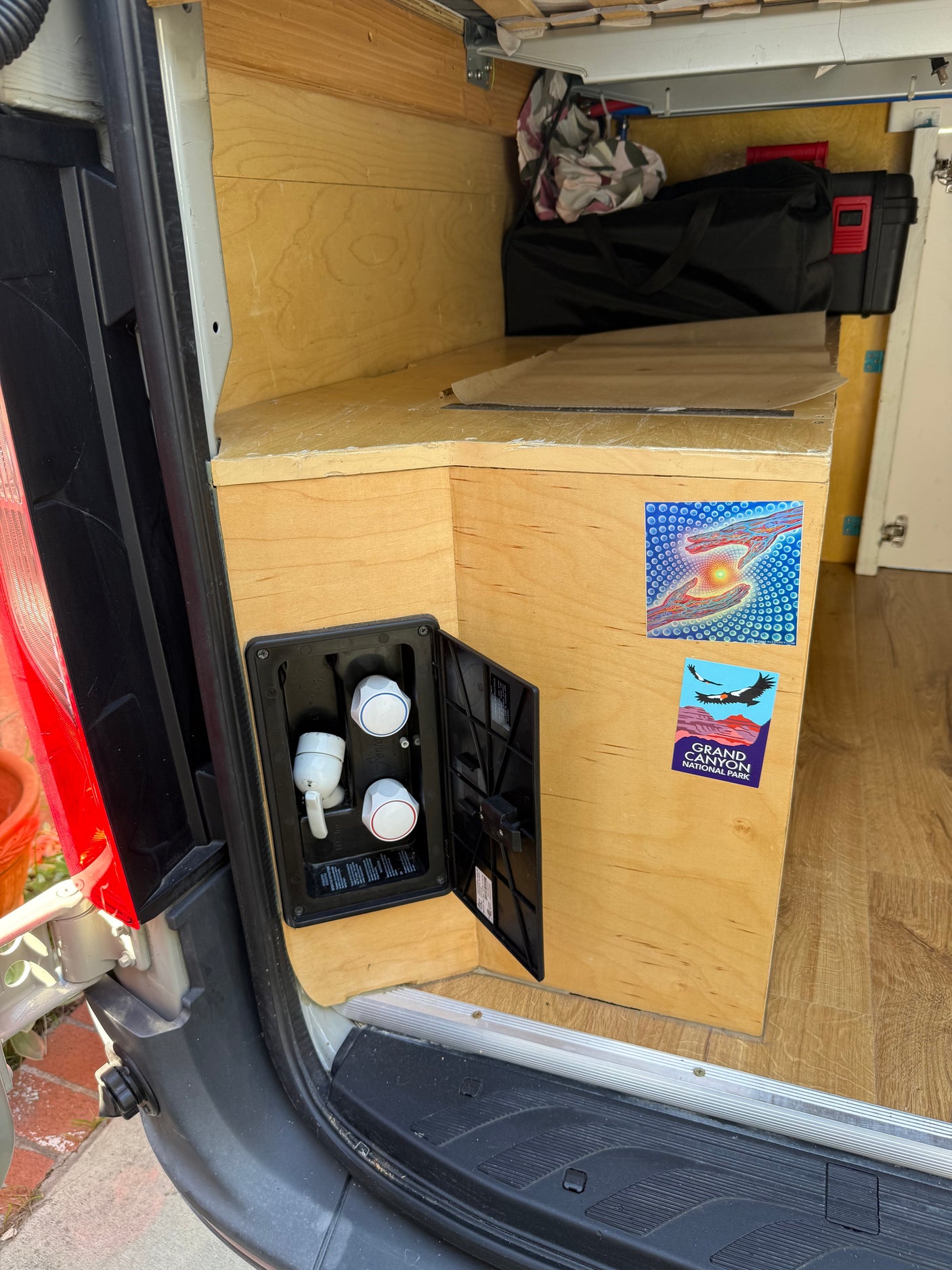 RV rental camper van interior. Custom wood build featuring an outdoor shower hookup, storage, and laminate flooring.
