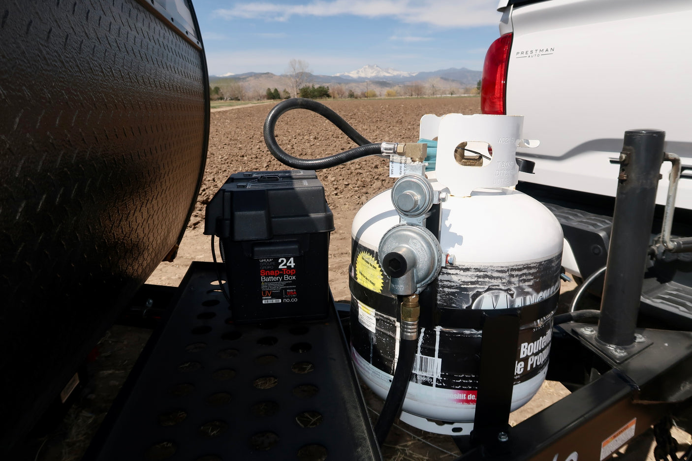 RV rental setup: Propane tank and battery box on a travel trailer tongue, ready for adventures with mountain views.