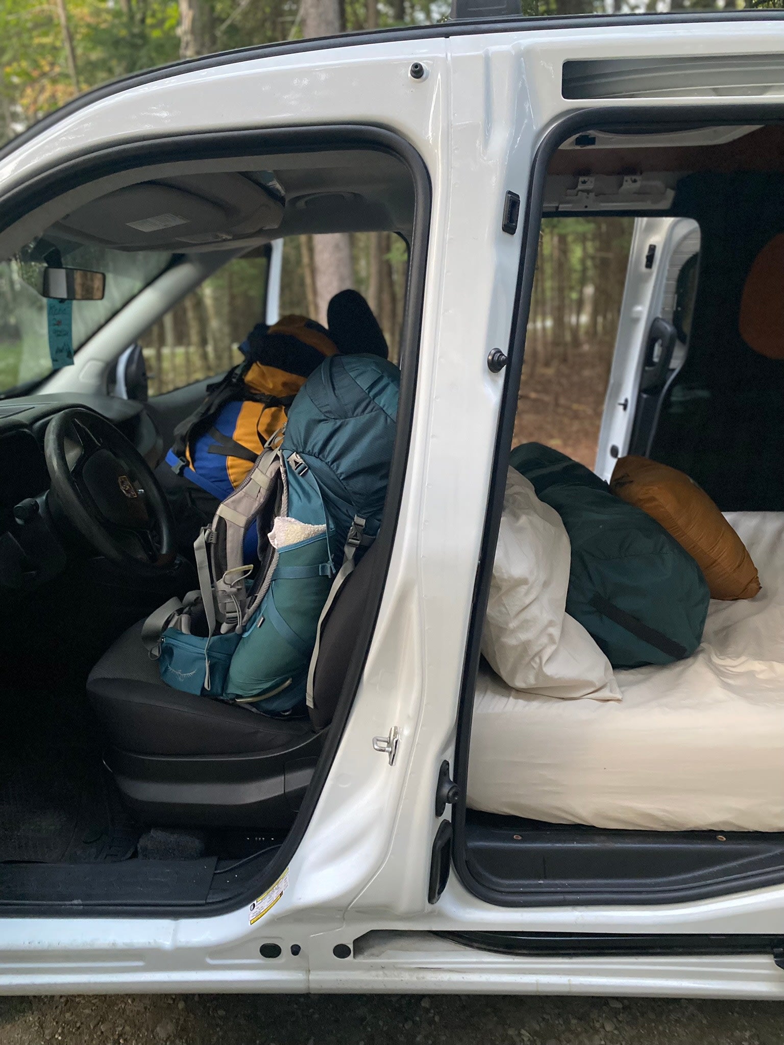 parked outside among trees.|Inside a cozy RV rental: a comfortable bed
