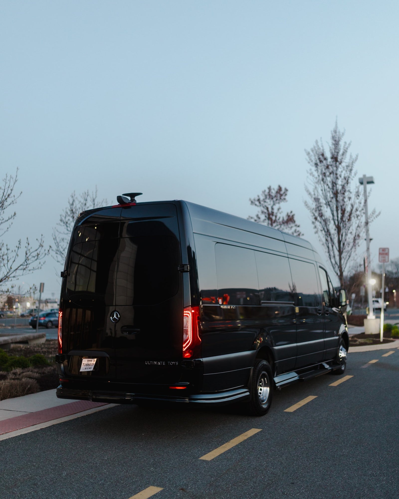 Black luxury Mercedes Sprinter van by Ultimate Toys, an ideal RV rental, parked at dusk.