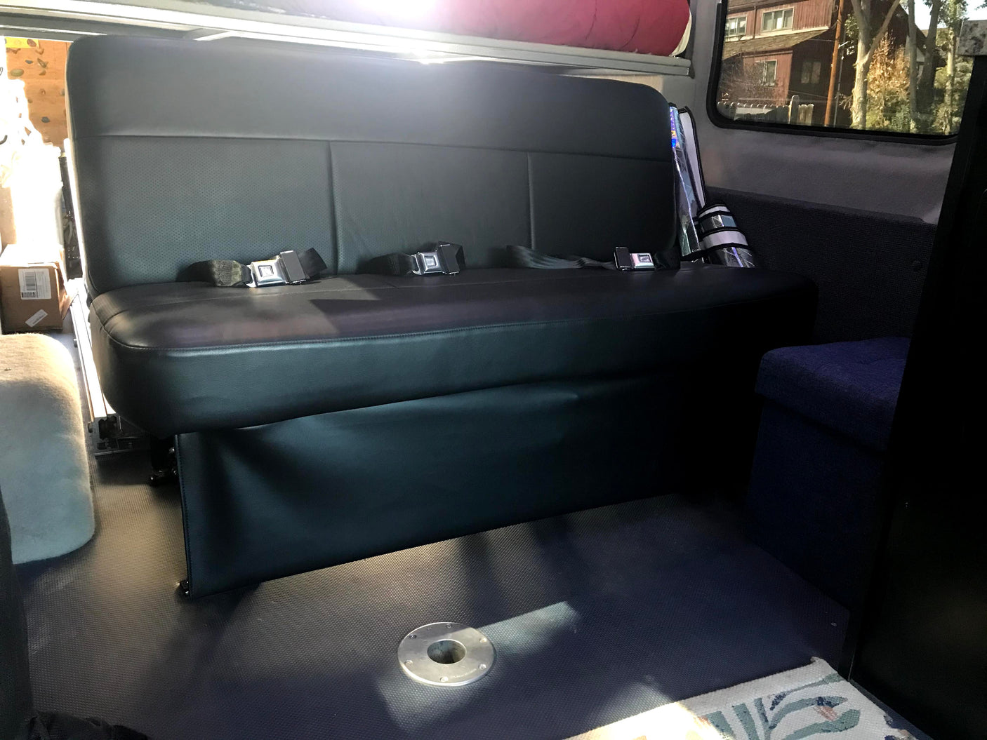 RV rental interior: spacious black bench seat with seatbelts, durable floor, and table base. Ready for adventures.