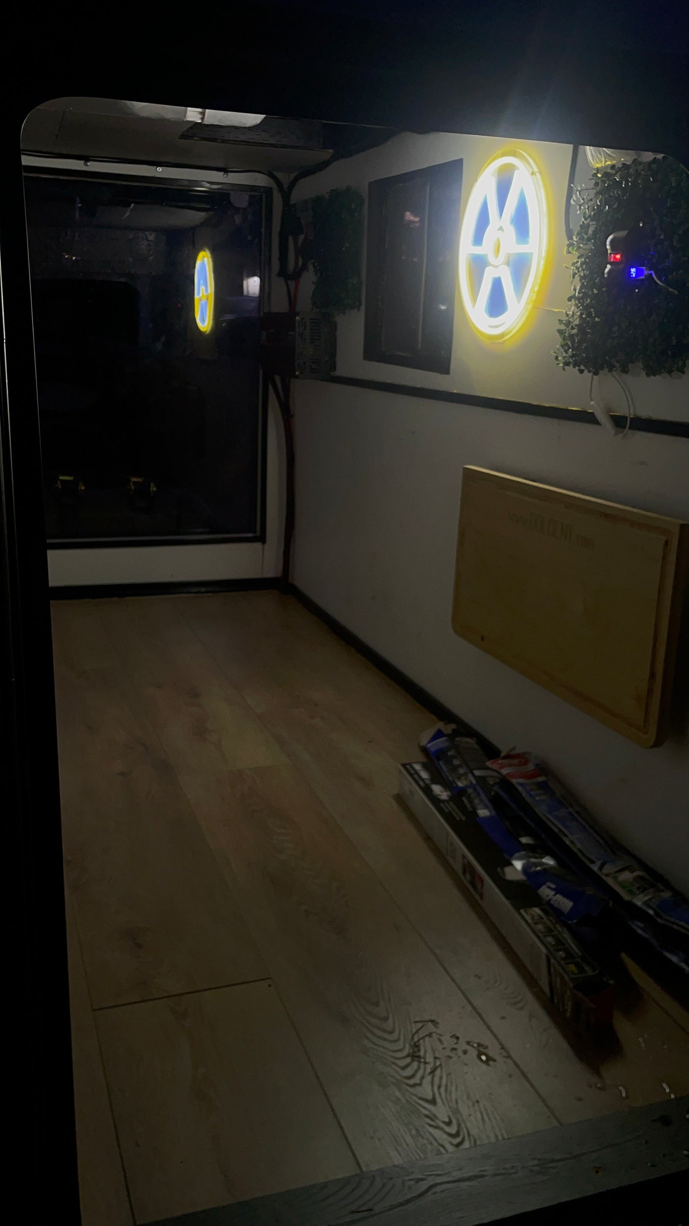 RV rental's cozy interior showcases wooden flooring, a unique glowing neon sign, and practical storage boxes.