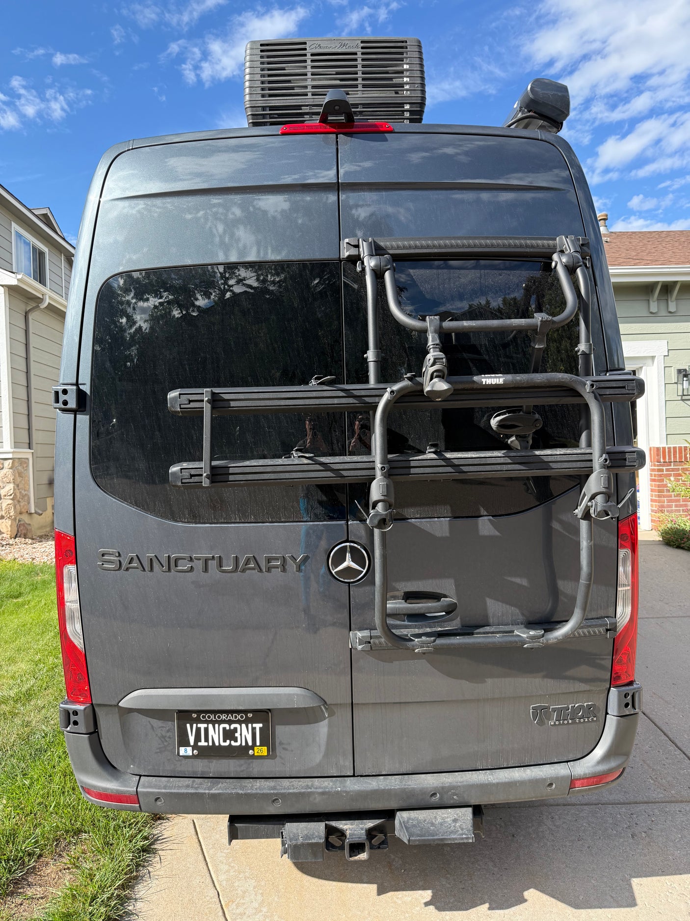 Back of a gray Mercedes-Benz Sprinter **rv rental** with a Thule bike rack, roof AC unit, and Colorado license plate.