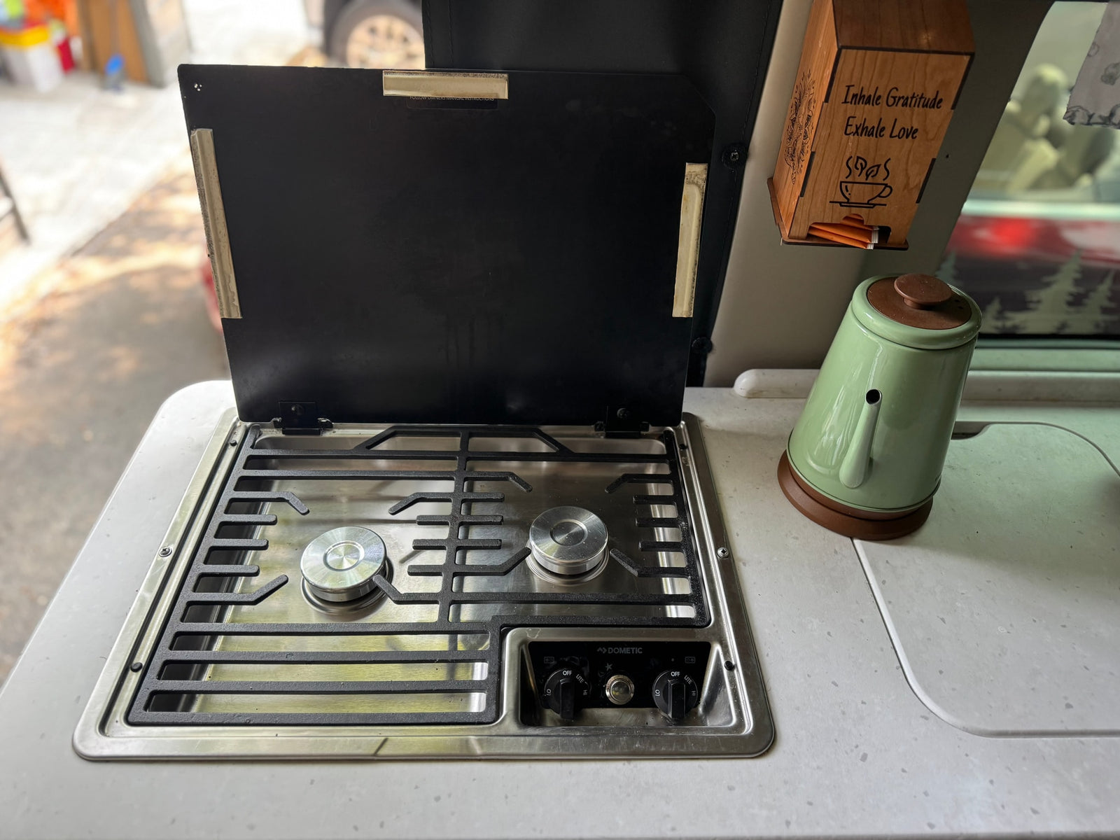 RV rental kitchen setup with a Dometic stove, kettle, and a tea bag dispenser on the counter, ready for travel meals.