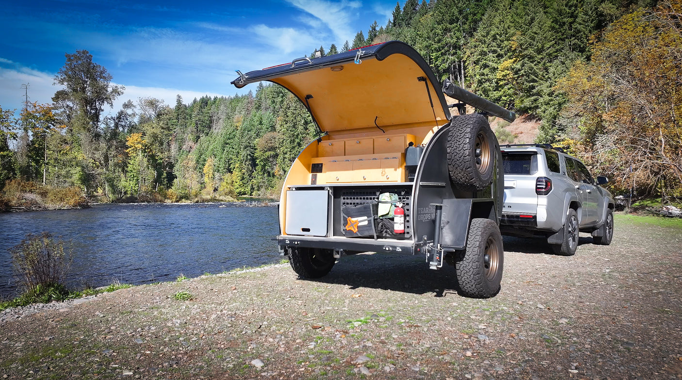 Enjoy riverside camping! This off-road teardrop trailer, towed by an SUV, is ideal for your next rv rental adventure.