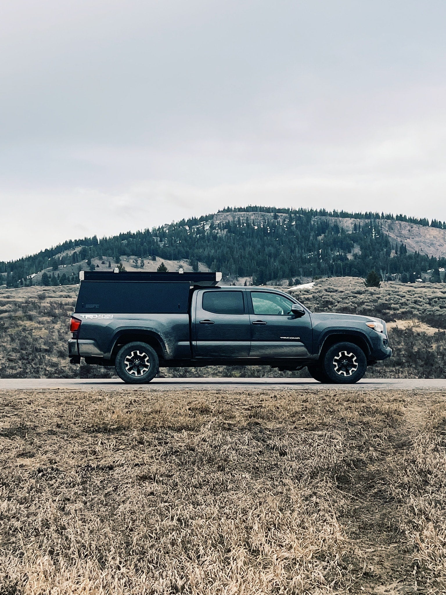 perfect for adventures.|RV rental: A TRD 4x4 truck with a bed camper on a forest road lined by giant trees