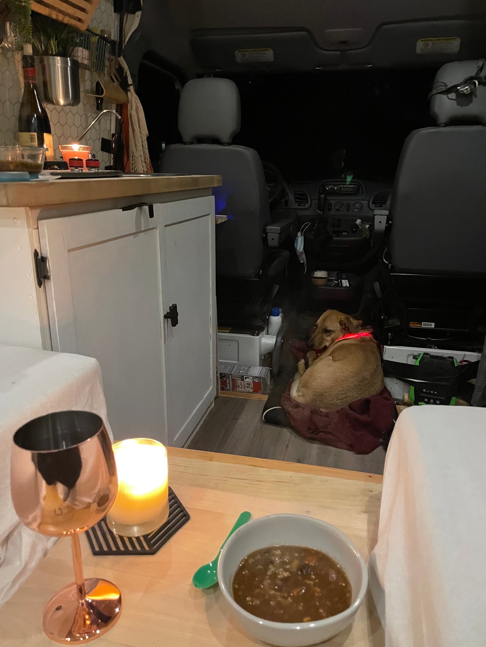 Cozy RV rental interior: dog snoozing, warm candle glow, and a hearty meal on a quiet night in.