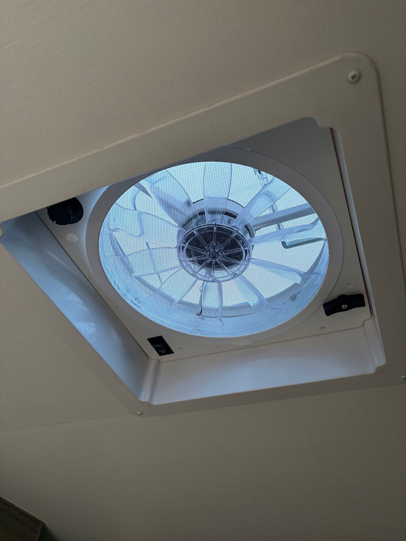 Ceiling fan/vent with mesh screen and controls in an RV rental, providing ventilation for comfortable travel.