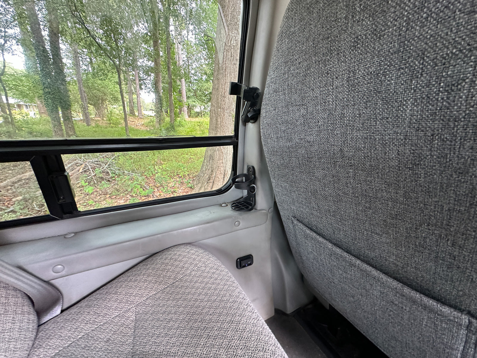 surrounded by trees and grass.|This white high-top Ford E-Series conversion van