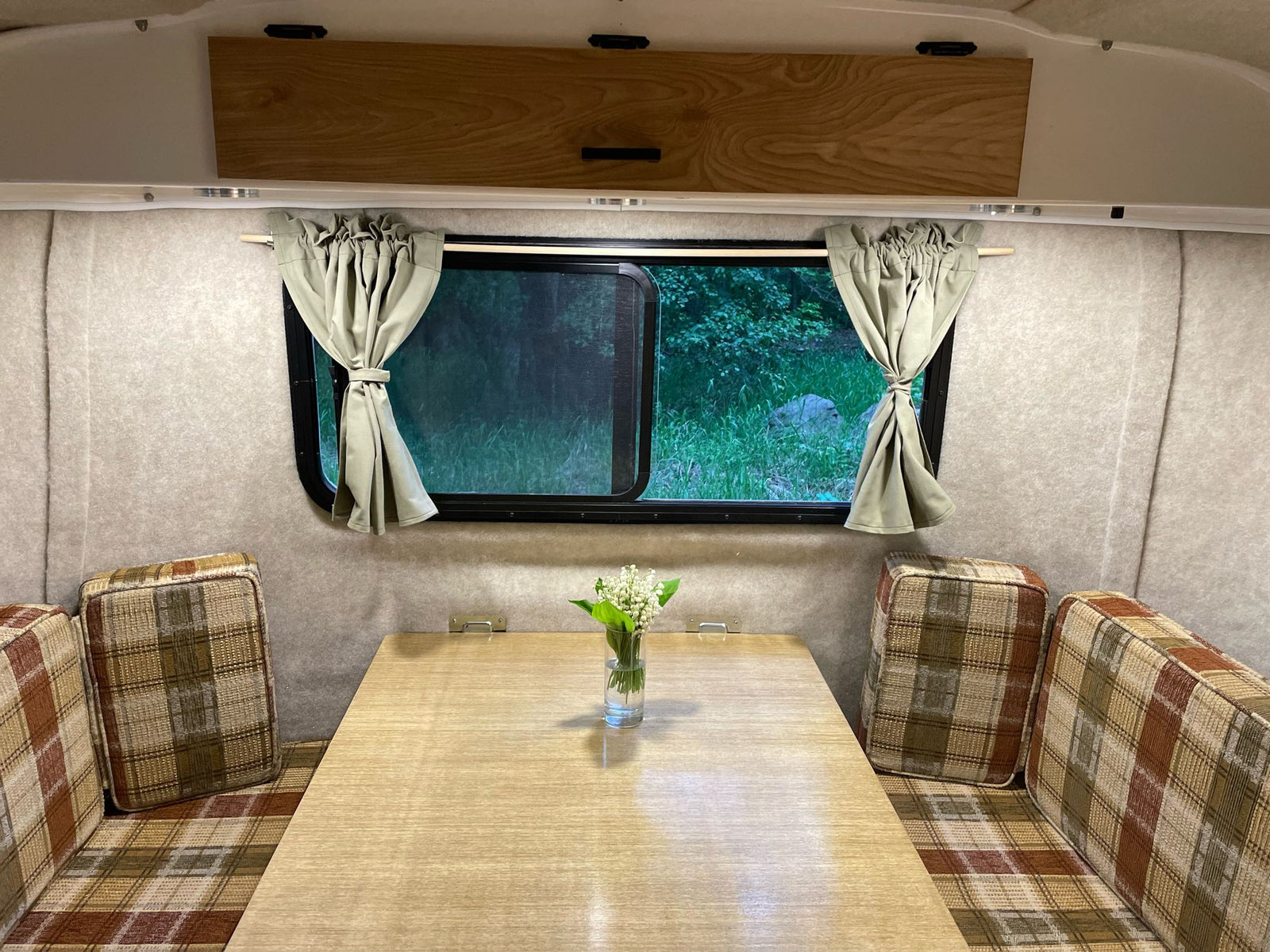 and charming wood paneling.|White Scamp travel trailer RV rental hitched to a red SUV by a lake