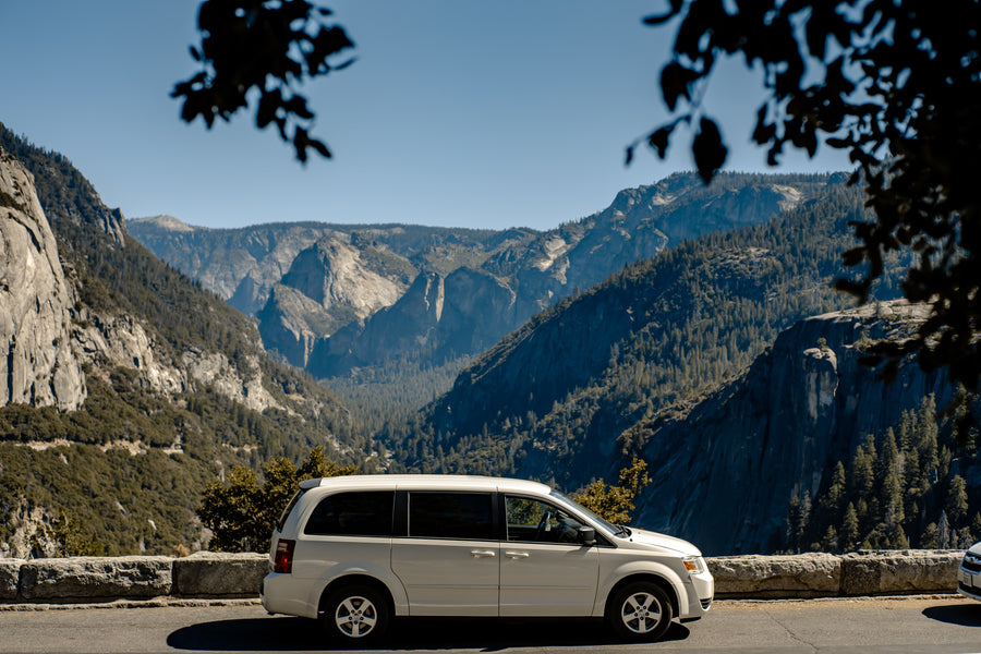 Scenic mountain vista with a white minivan parked. Explore similar grand views and forests on your next rv rental adventure.