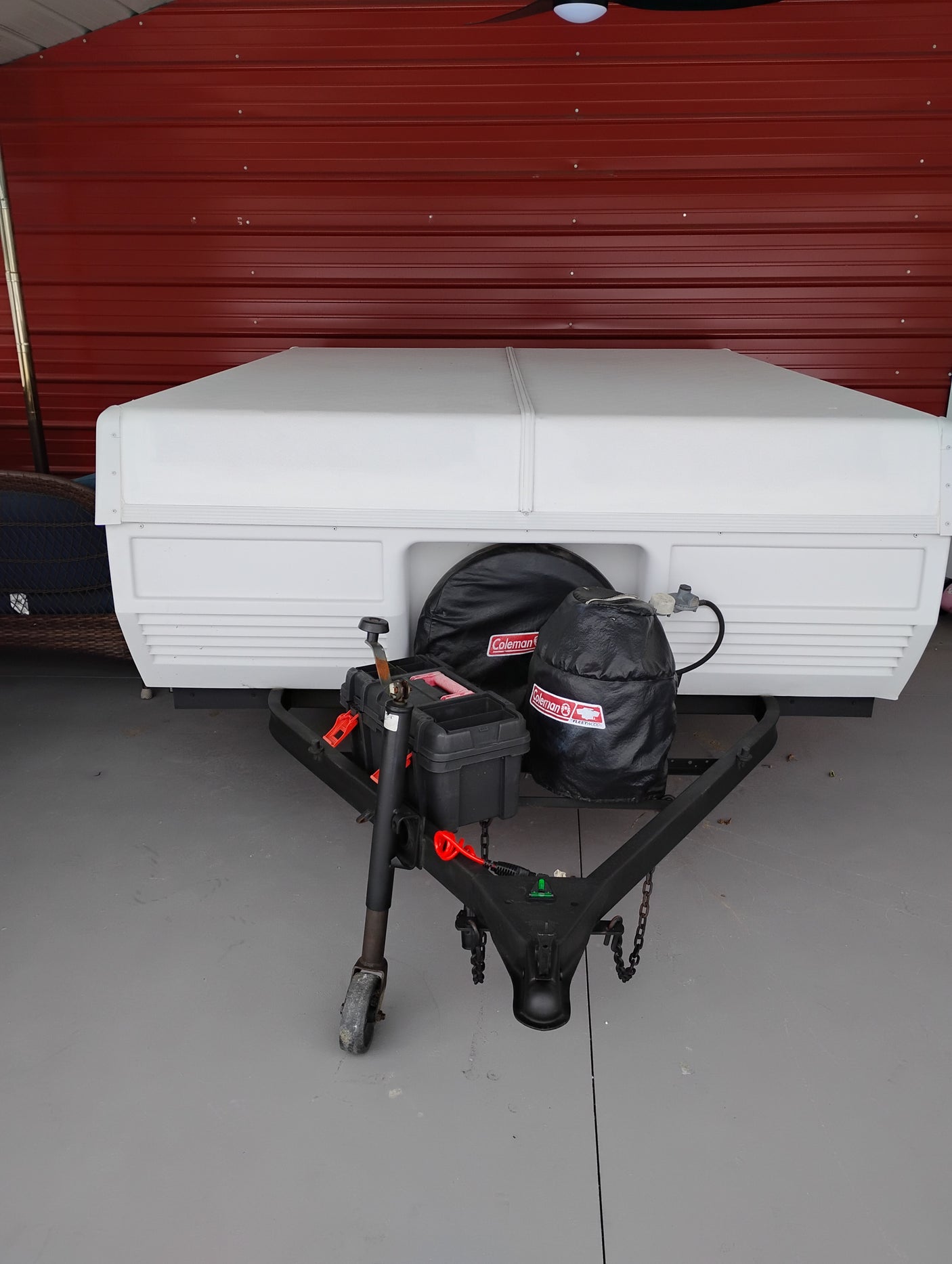 Front view of a white Coleman pop-up camper, an excellent RV rental option, showing hitch and essential gear.
