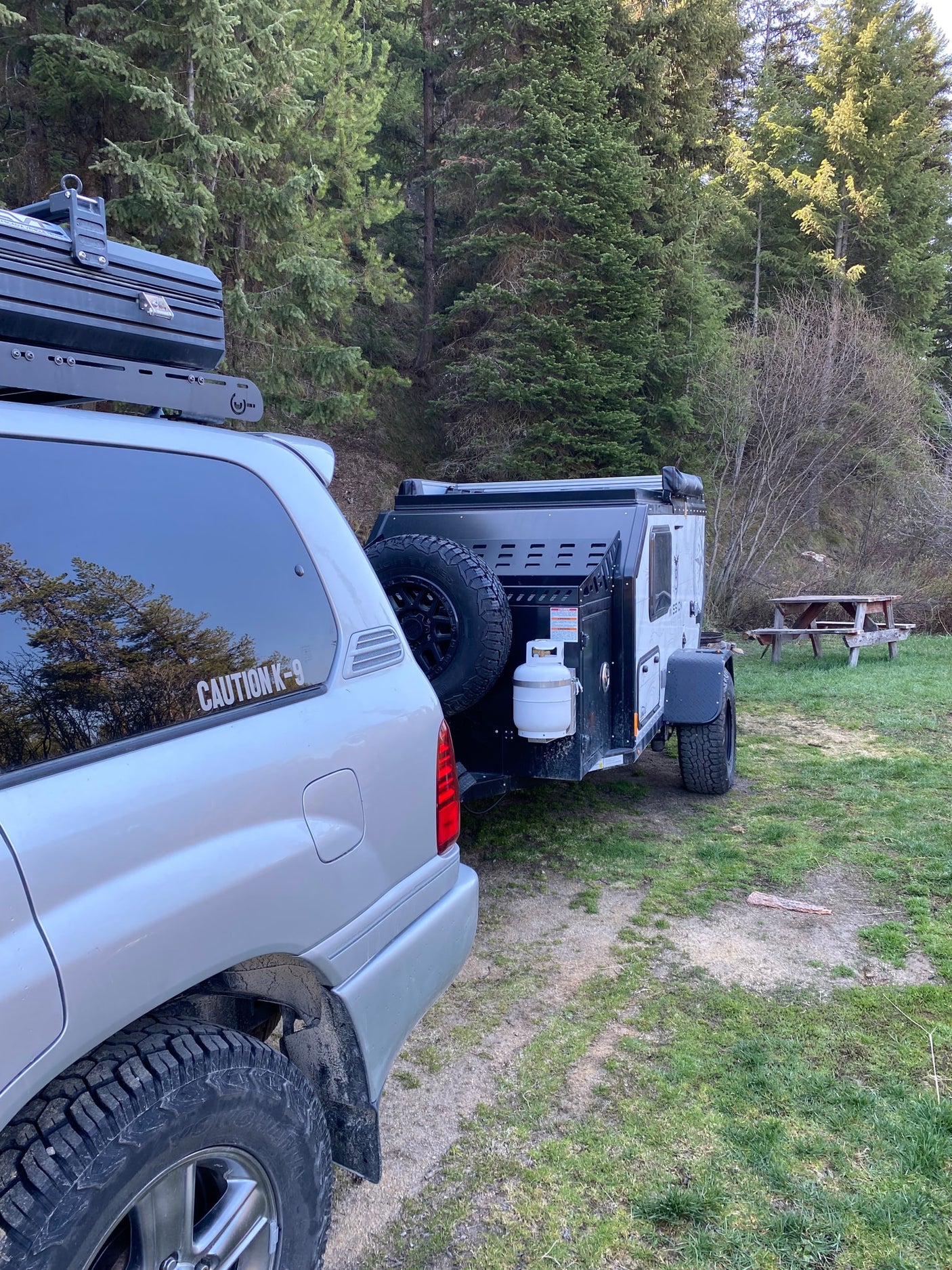 and a gravel floor for outdoor comfort.|RV rental adventure: Silver SUV tows a pop-top off-road camper with awning and lights