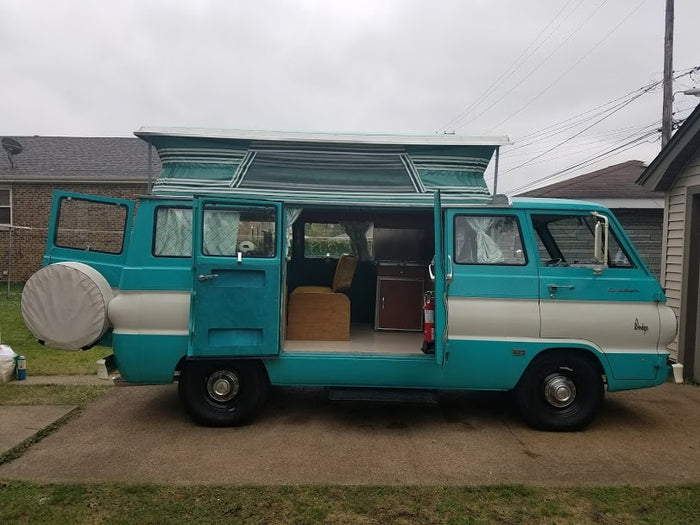 revealing its classic interior setup. Perfect for an RV rental adventure.|Vintage teal & white pop-top Dodge camper van