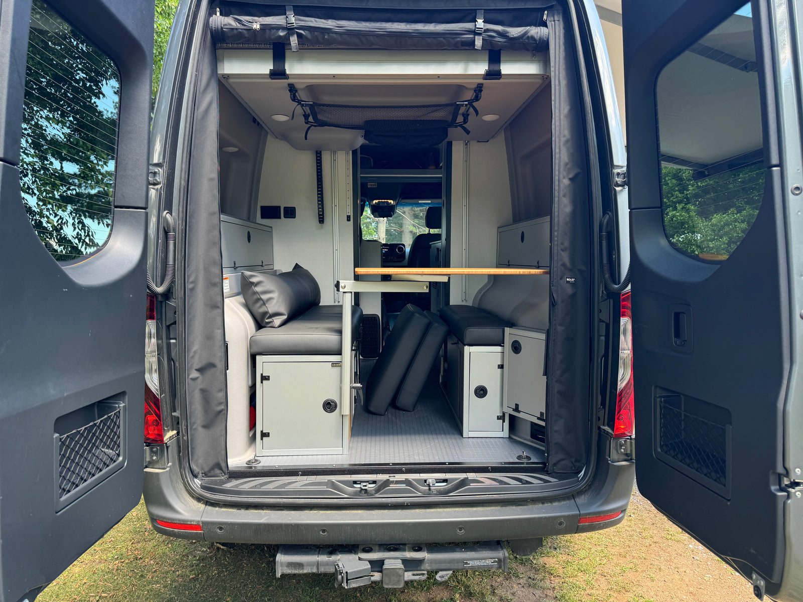 Explore this **RV rental's** versatile **camper van interior** with modular **seating**, **table**, and **storage**, ready for adventure.