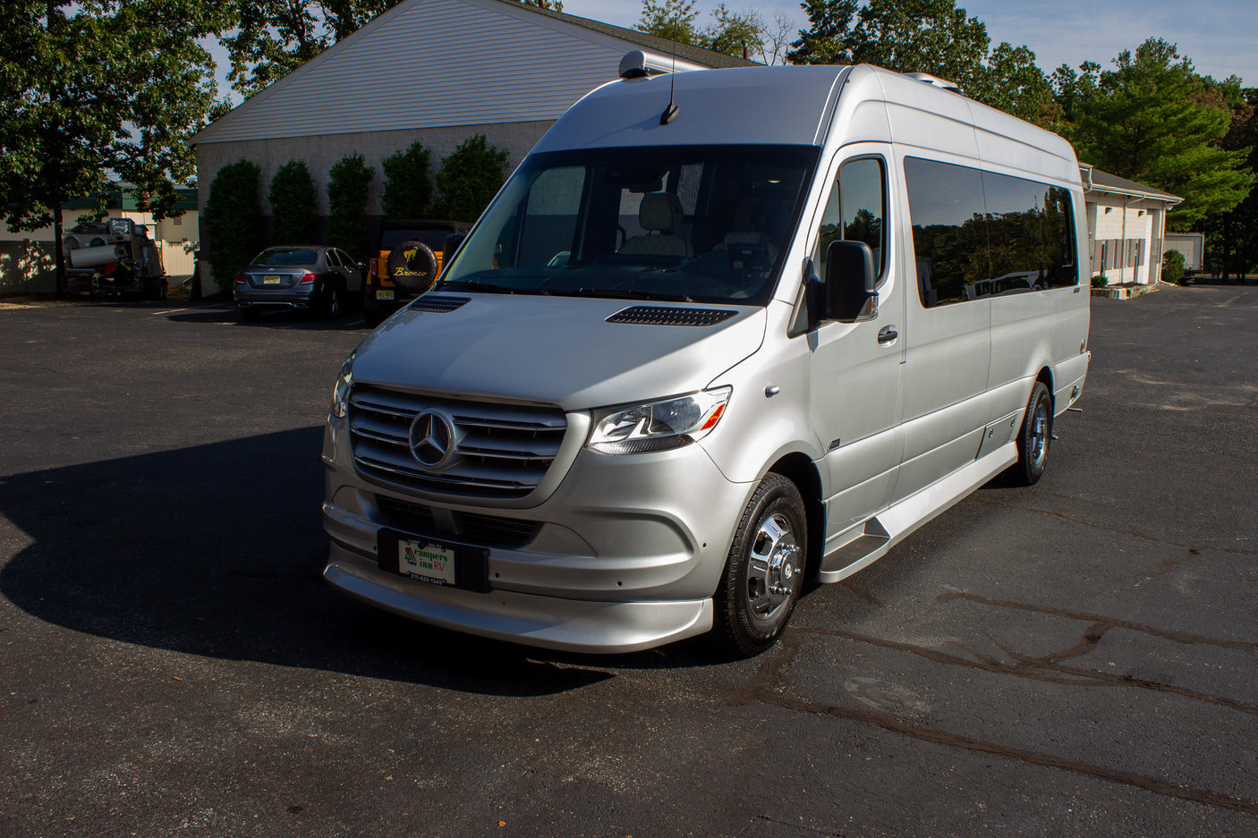 Silver Mercedes-Benz Sprinter RV rental from Campers Inn RV, parked on an asphalt lot in daylight.