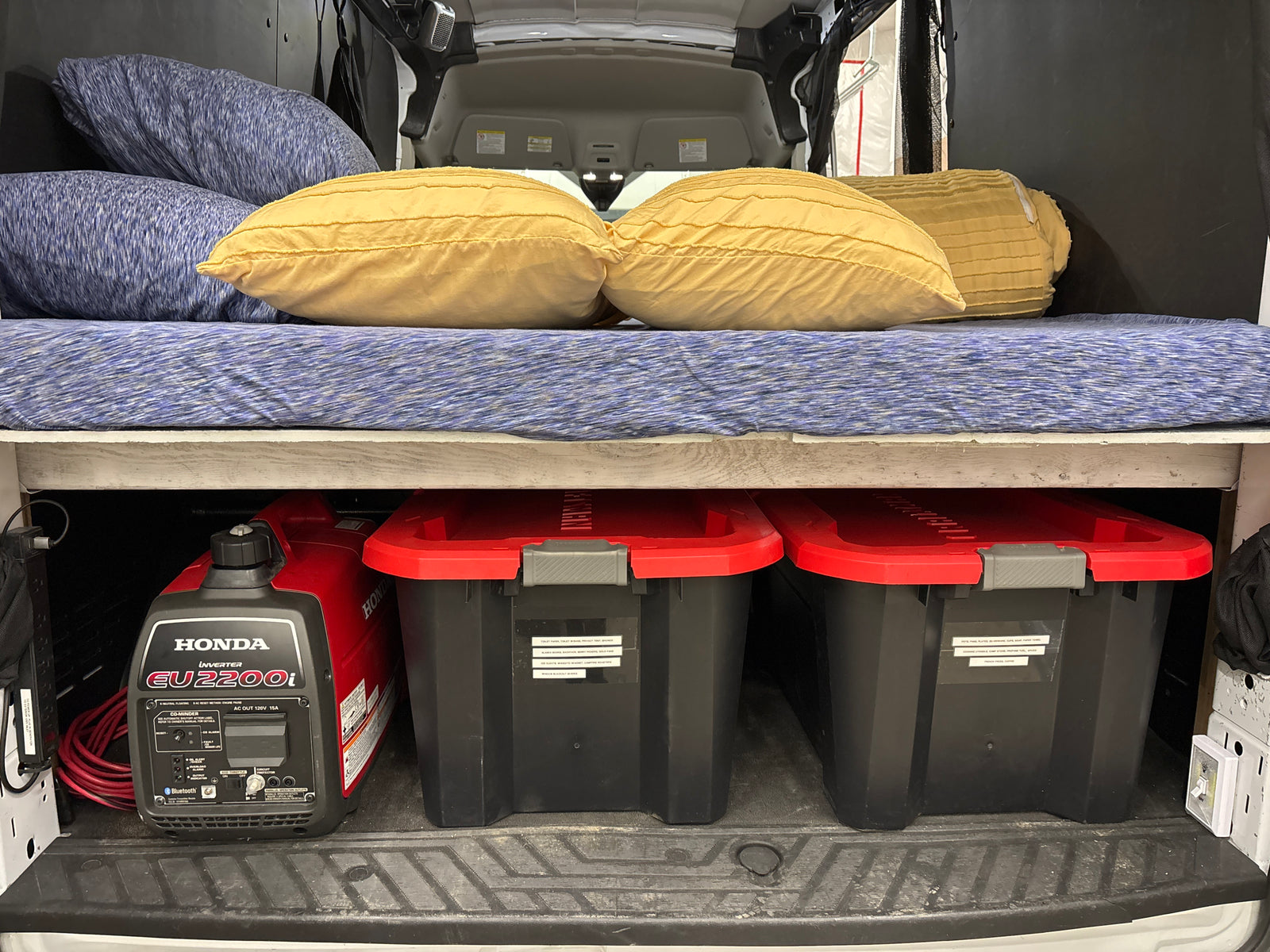 RV rental: Honda EU2200i generator and organized bins under a comfy bed, ideal for van life camping.