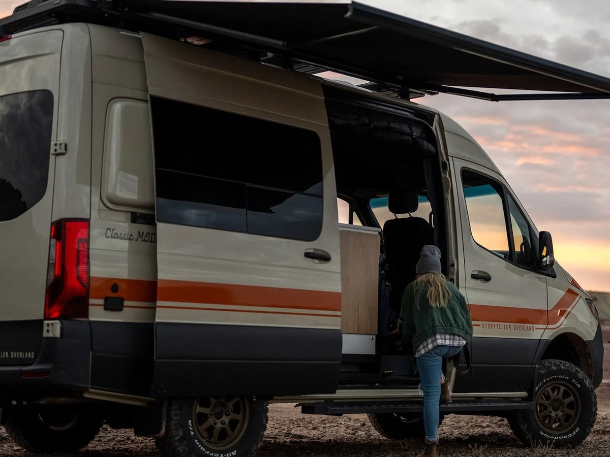 an rv rental ready for sunlit adventures on a dirt road.|Adventure awaits with this Storyteller Overland rv rental. A person steps into the van with its awning extended at sunset.|Cozy rv rental interior: bed — photo 2