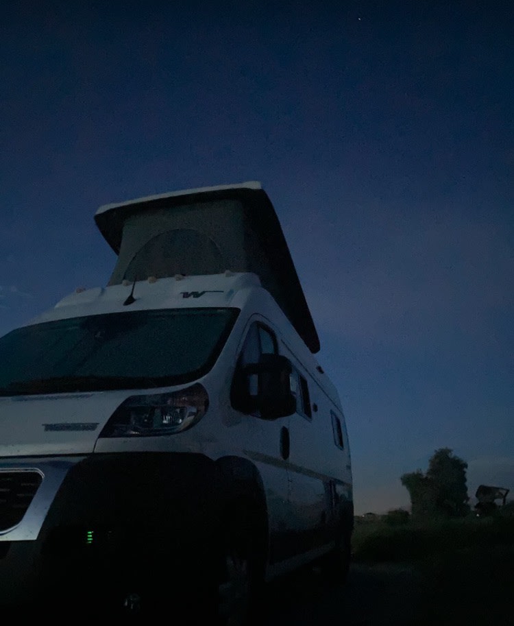 White pop-top camper van under a deep blue dusk sky. Your ultimate RV rental adventure awaits!