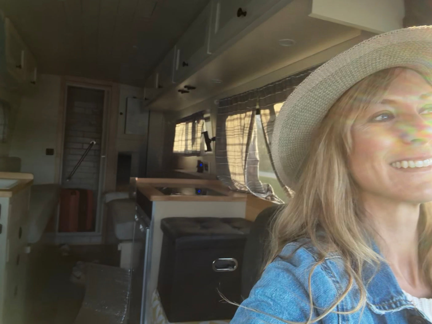 Smiling woman in her spacious RV rental, showcasing the comfortable interior with kitchen and cabinets.