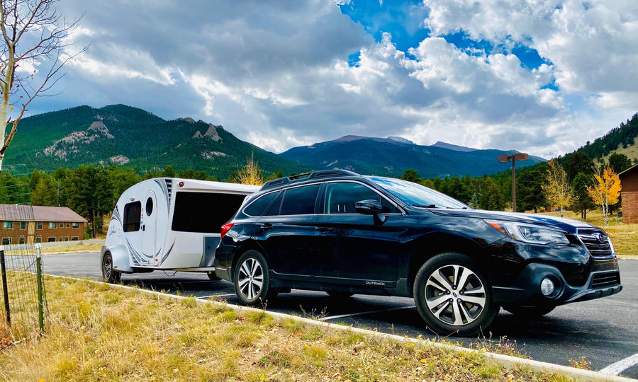 Black Subaru Outback towing a white Luna RV rental