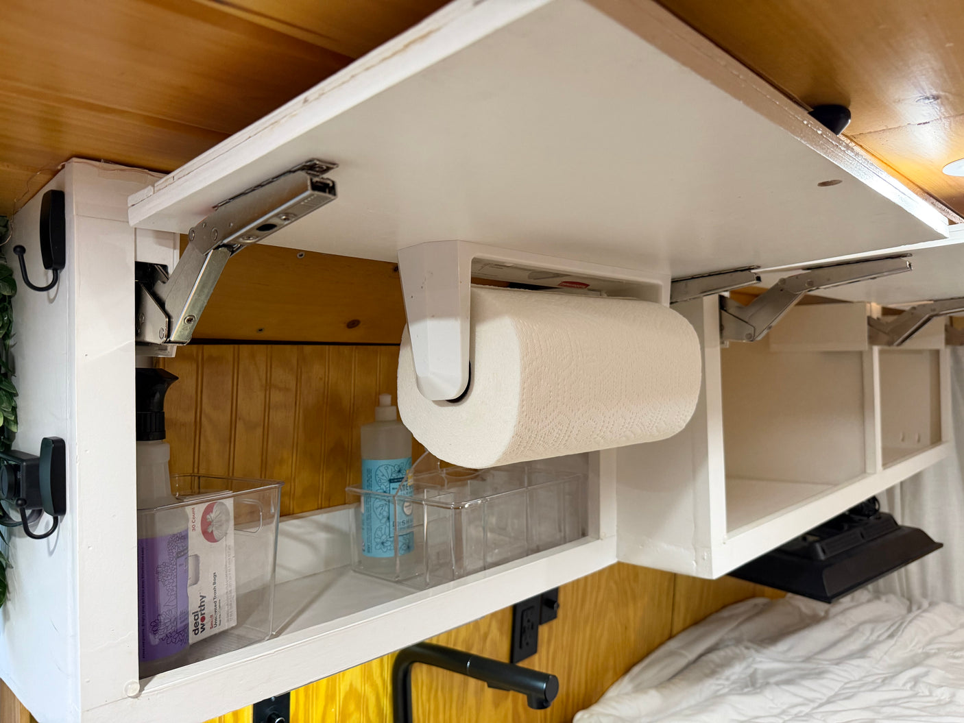 Inside an RV rental: An organized overhead cabinet holds paper towels, cleaning items, and bins for smart travel storage.