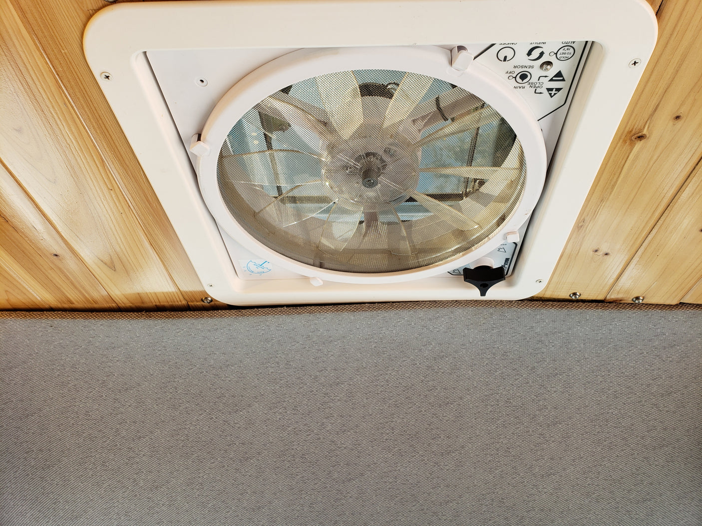 Ceiling-mounted MaxxAir fan in an RV rental, showing controls for airflow, rain sensor, and temperature settings.