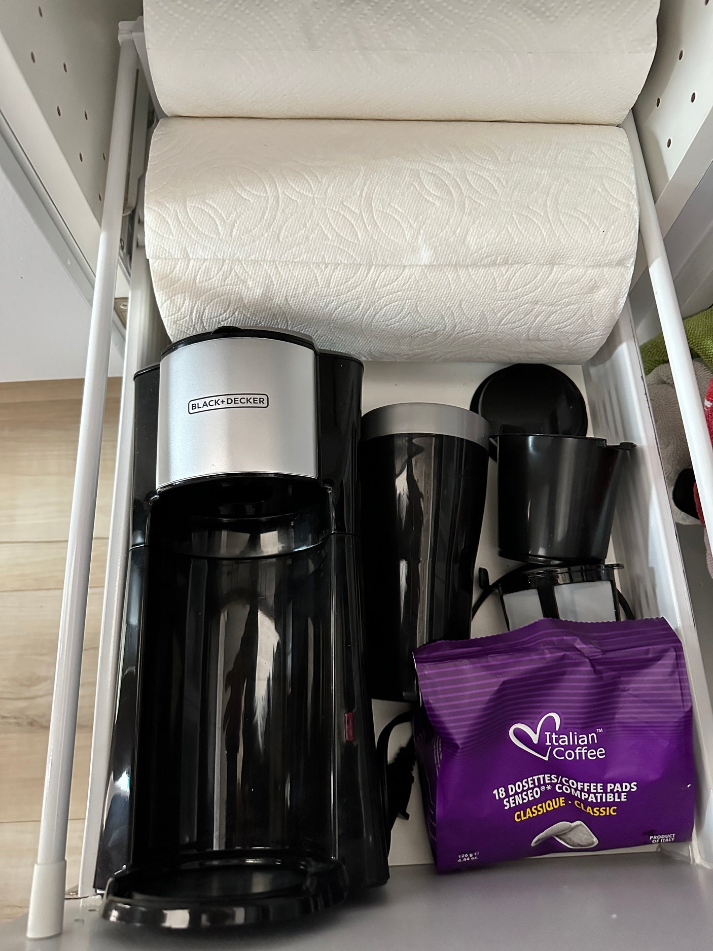Black+Decker coffee maker, coffee pads, and paper towels neatly organized for an rv rental kitchen.