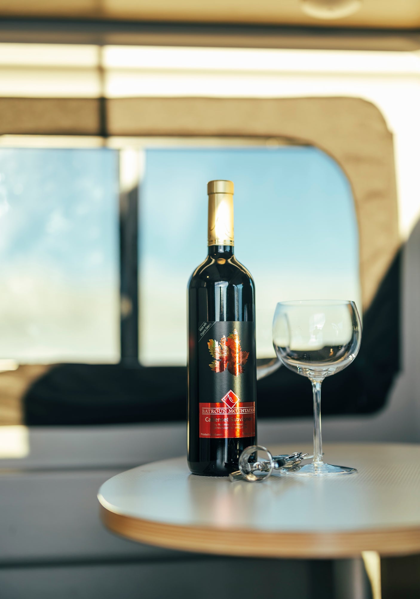 An organic Cabernet Sauvignon bottle, glass, and opener on a table inside an RV rental. Perfect for travel.