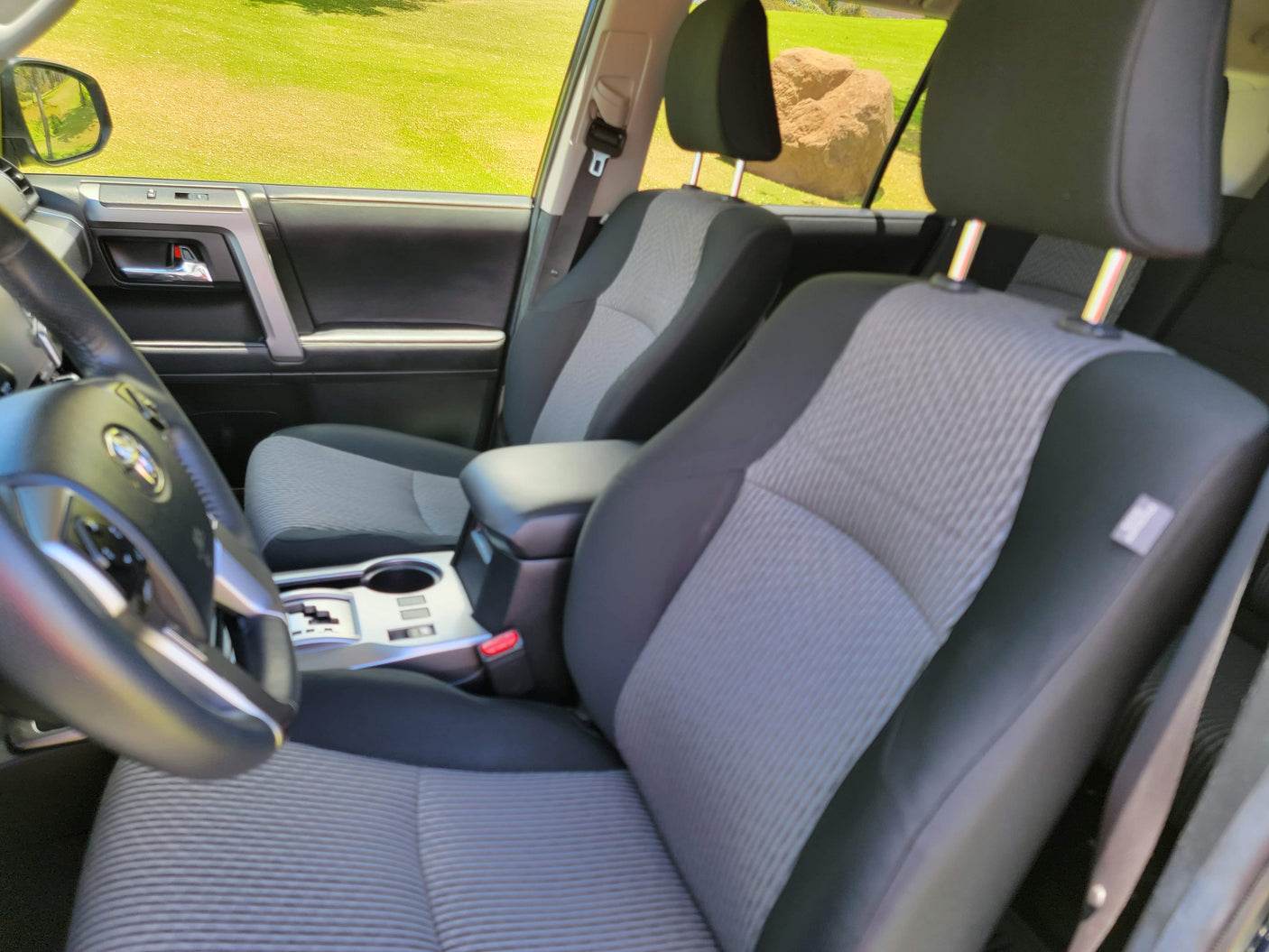 Car interior with gray/black fabric seats, steering wheel, and console, seen from driver's side. Ideal for your RV rental trip.