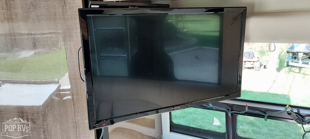 Enjoy entertainment in your RV rental! View of a TV mounted in the living space with outdoor scenery visible through windows.