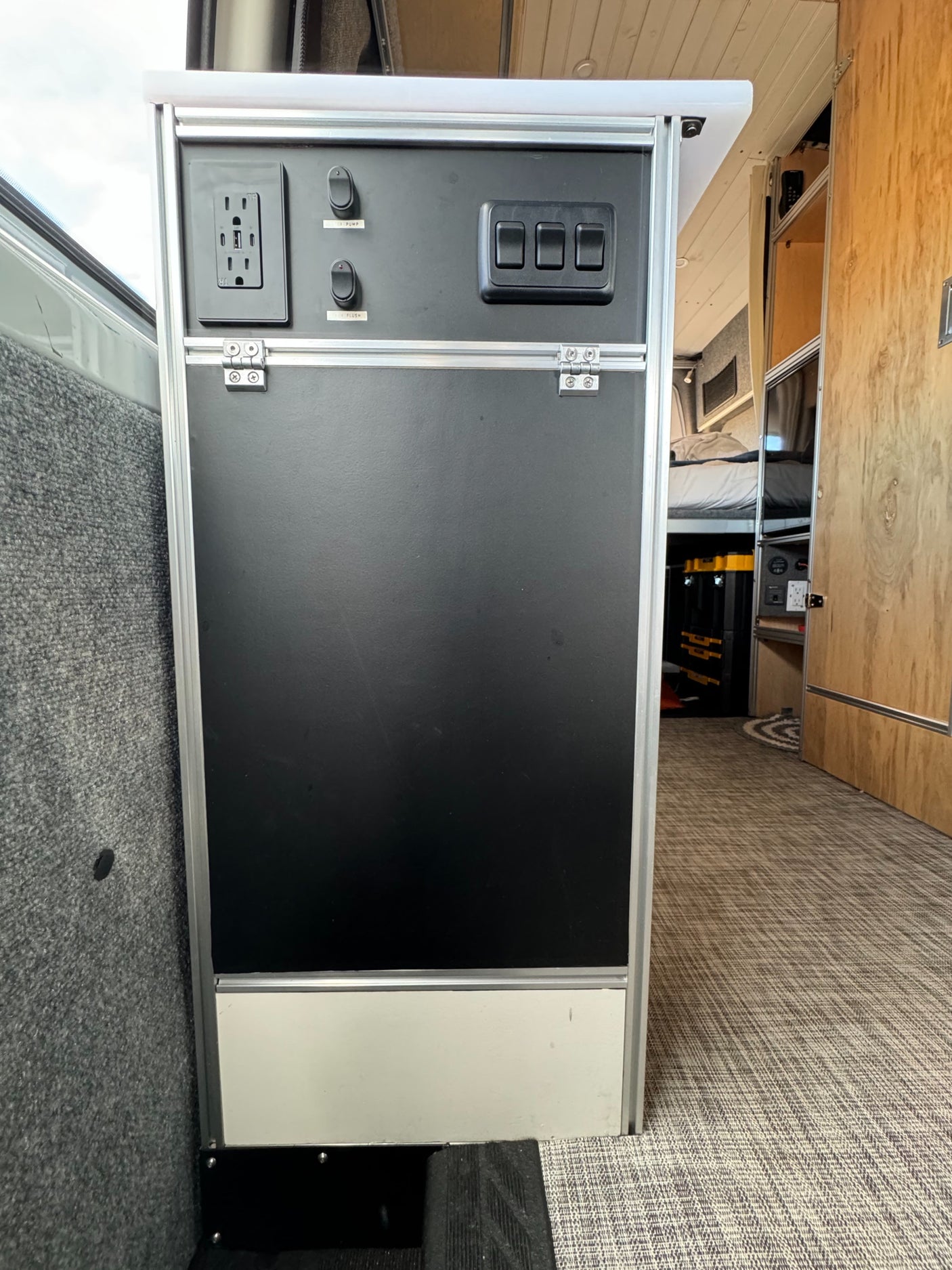 RV rental interior control panel with AC/USB outlets and switches for pump/flush systems, providing onboard utilities.
