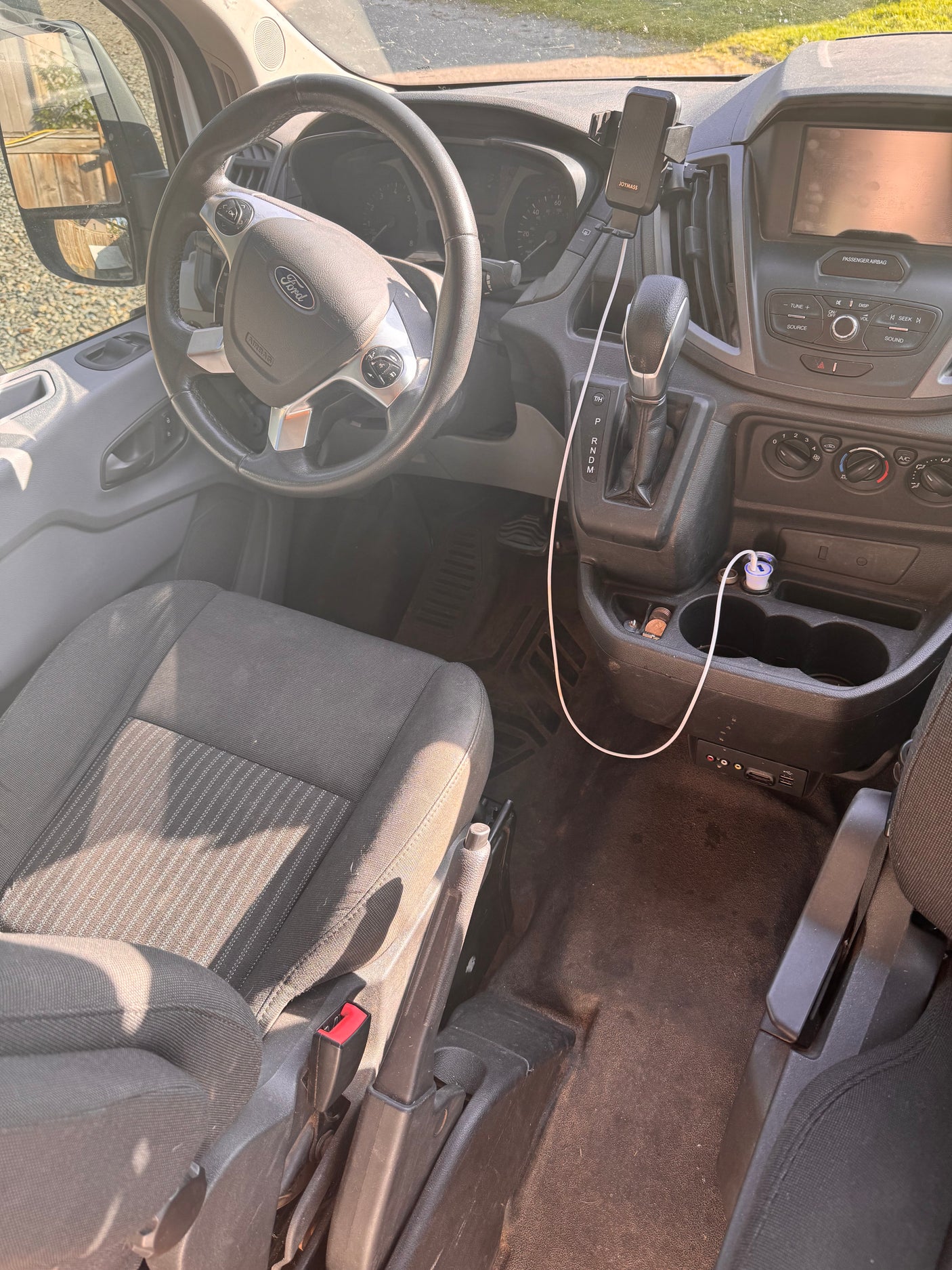 Ford van interior ready for an RV rental adventure. Driver's seat, dashboard, console, and media ports for comfort.