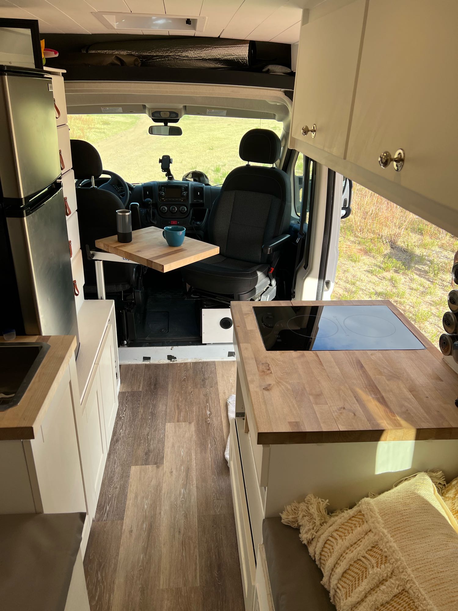 Modern RV rental interior: fully equipped kitchen, dining area, fridge, and cozy living space with bed.