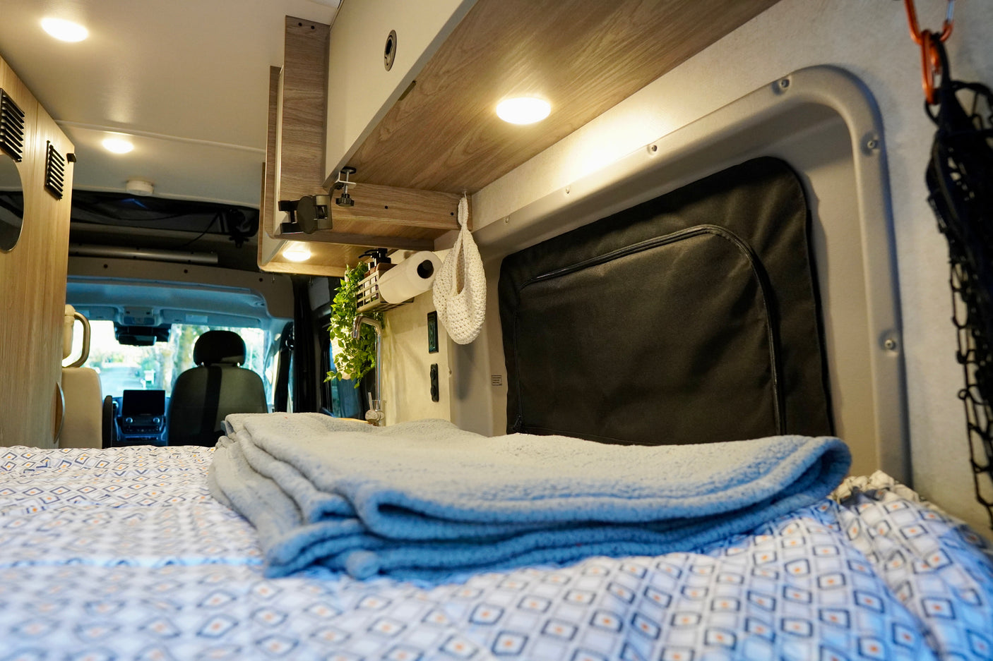 Cozy RV rental interior: bed, kitchen area, and cab view. Perfect for your next adventure.