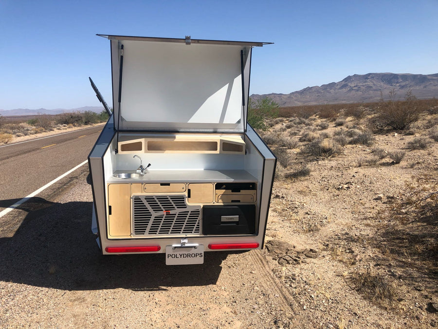 light wood paneled camper bedroom with skylight.|Stylish and functional outdoor kitchen in an rv rental