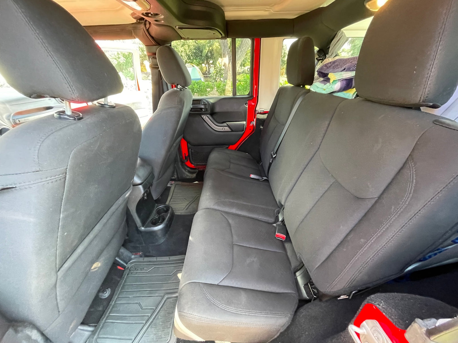 Rear view of an **RV rental** Jeep interior, showing comfortable black fabric seats and durable floor mats. Ideal for adventures.