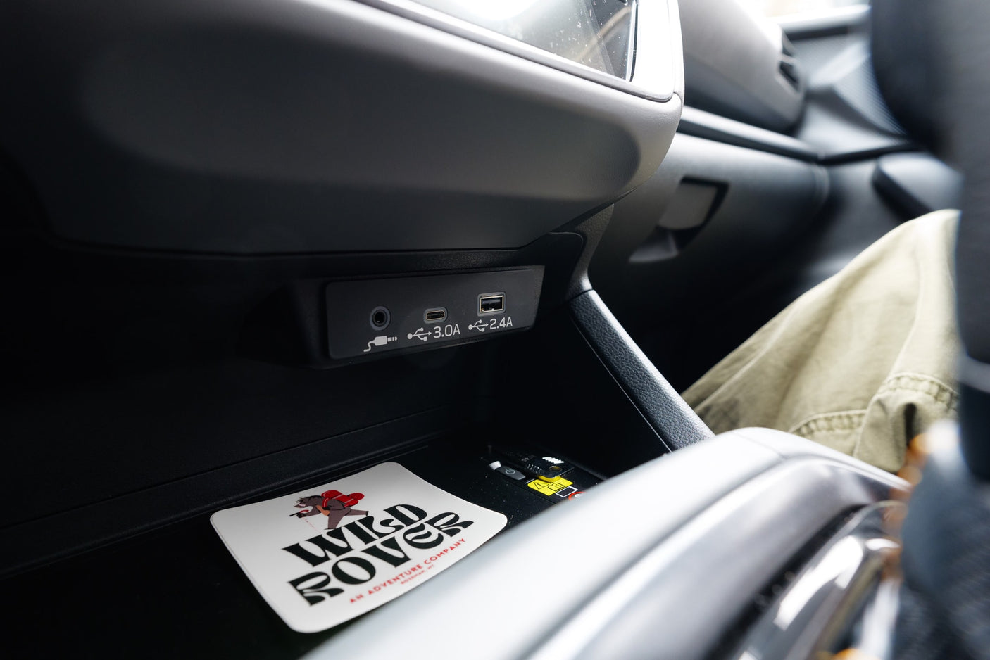Modern RV rental interior: USB-C/A charging ports, audio jack, and a "Wild Rover" coaster for your adventure.