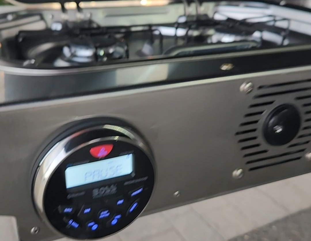 RV rental kitchen featuring a gas stovetop and integrated BOSS entertainment unit showing 'PAUSE'.