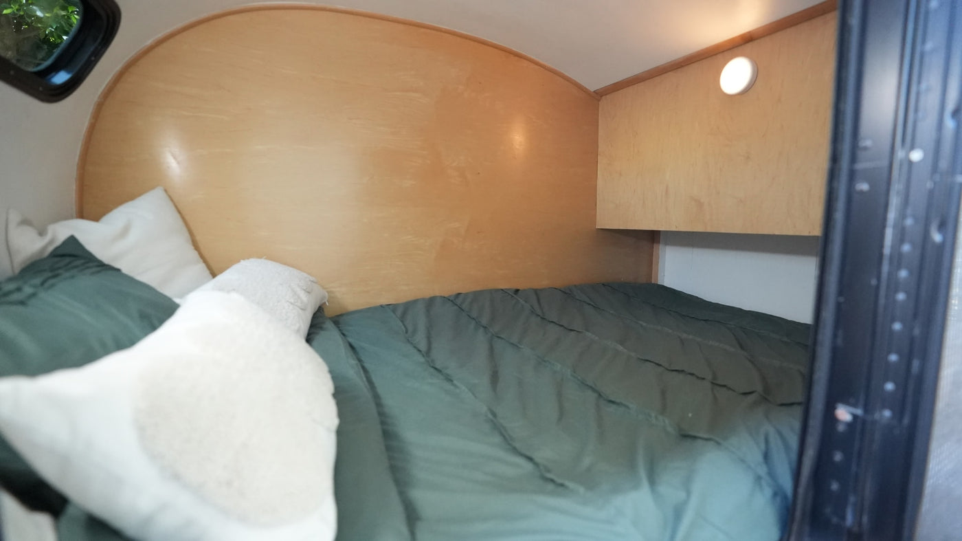 and bed for a perfect outdoor escape.|RV rental: White camper van towing a silver teardrop trailer parked by ocean rocks — photo 4
