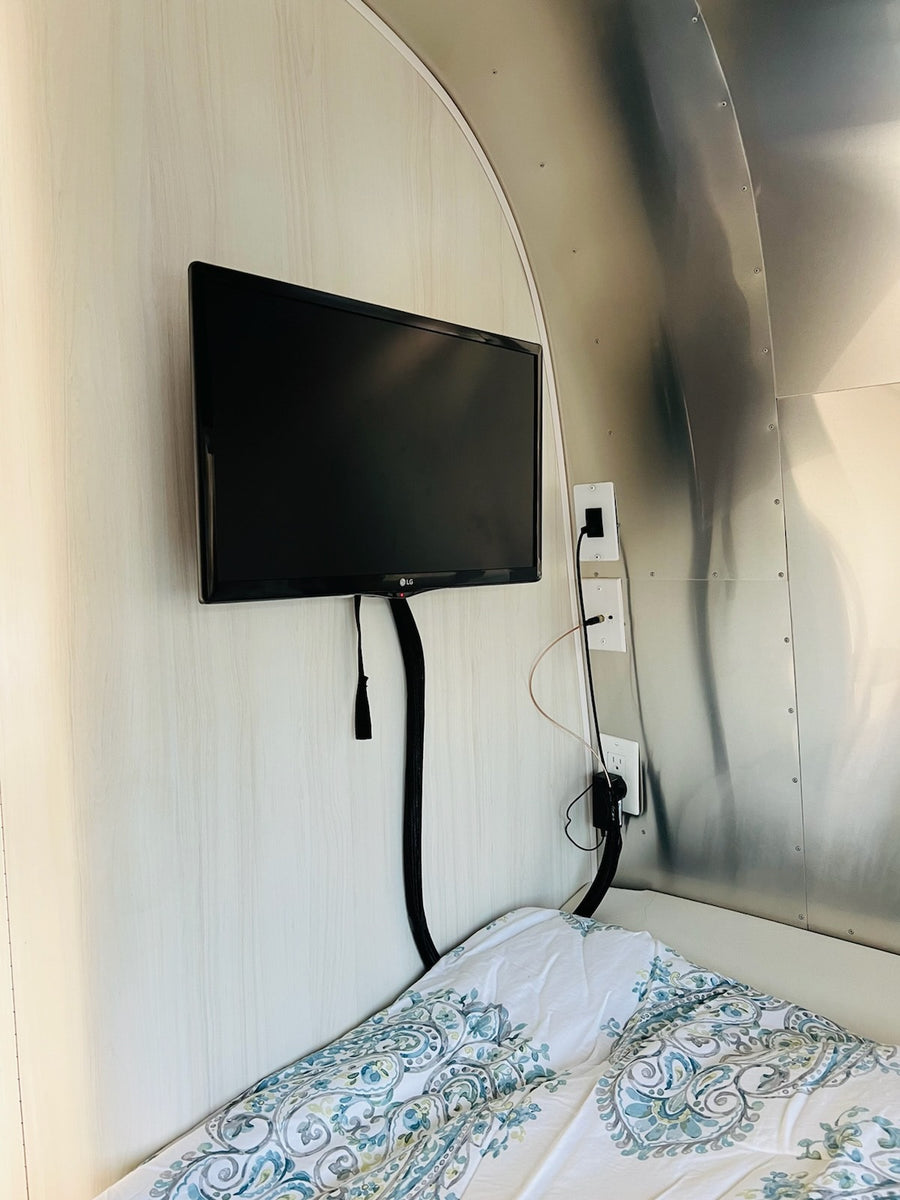 RV rental: A compact interior with a TV mounted above a comfortable bed and sleek metallic walls.