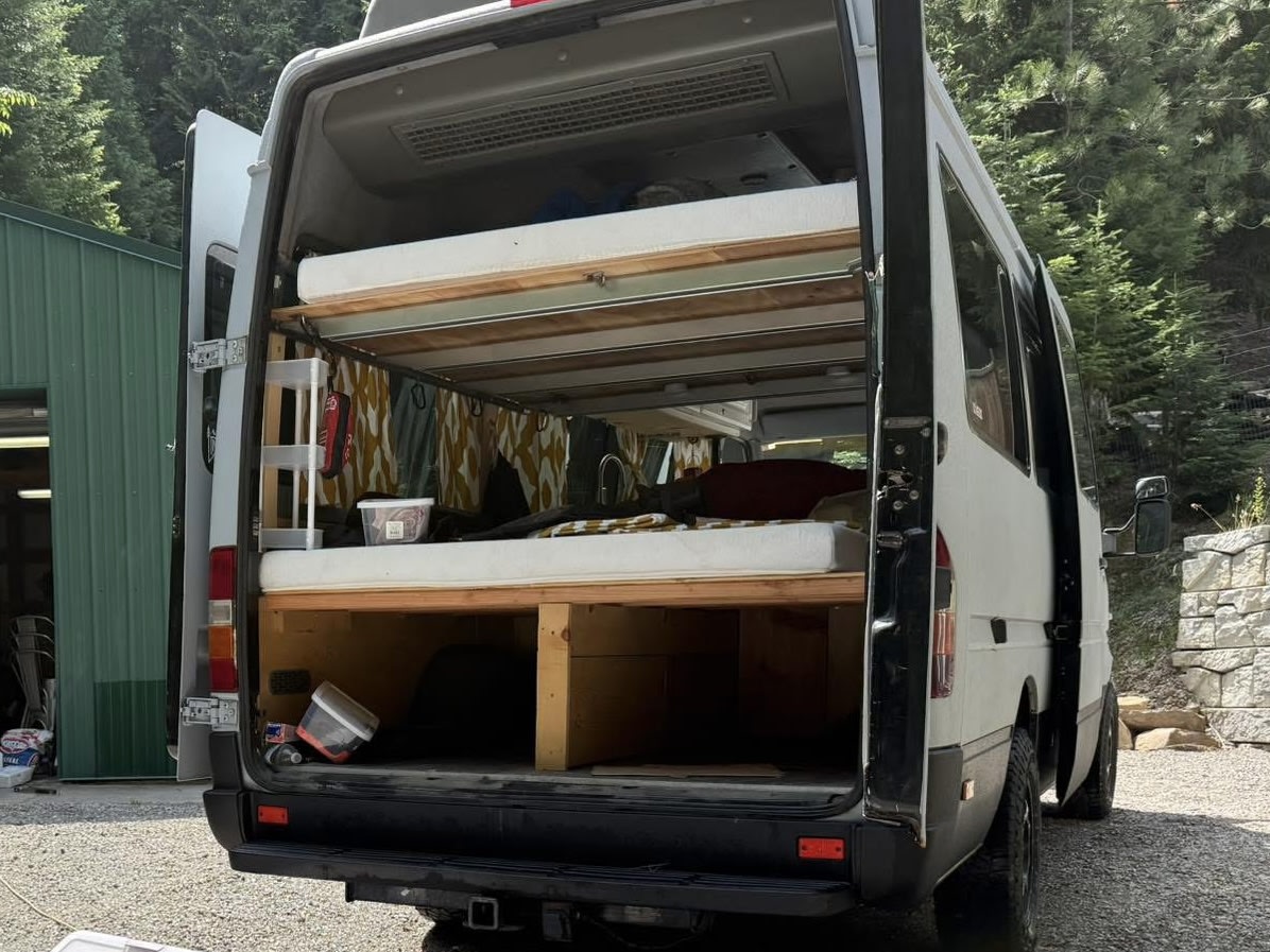 and a patterned privacy curtain.|Cozy RV rental camper van interior with bunk beds