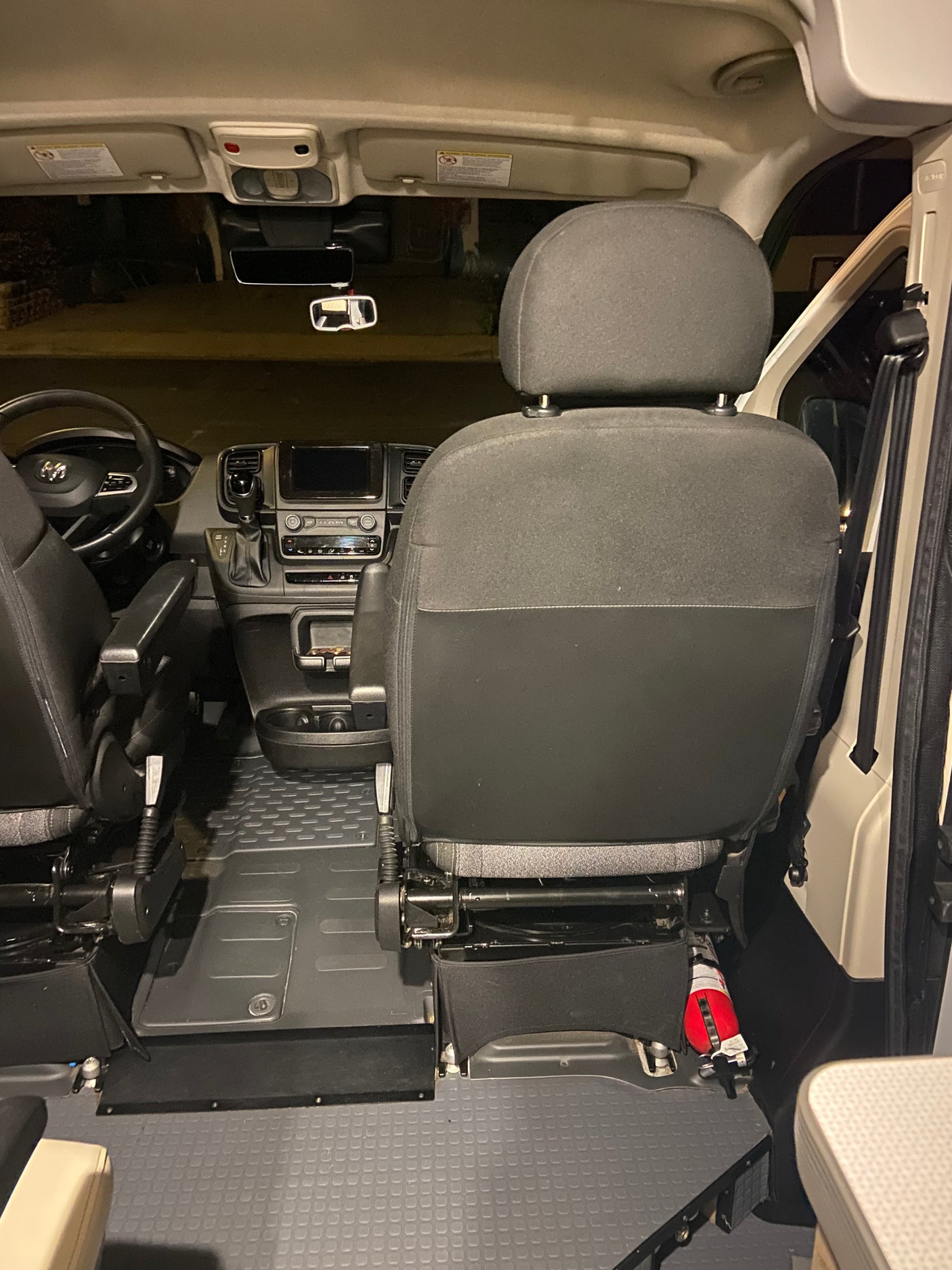Experience the interior of this rv rental. Driver's cockpit view shows dashboard, steering, seats, and fire extinguisher.