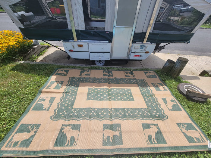 showcasing its roomy interior and outdoor mat.|This white and green pop-up camper is fully set up