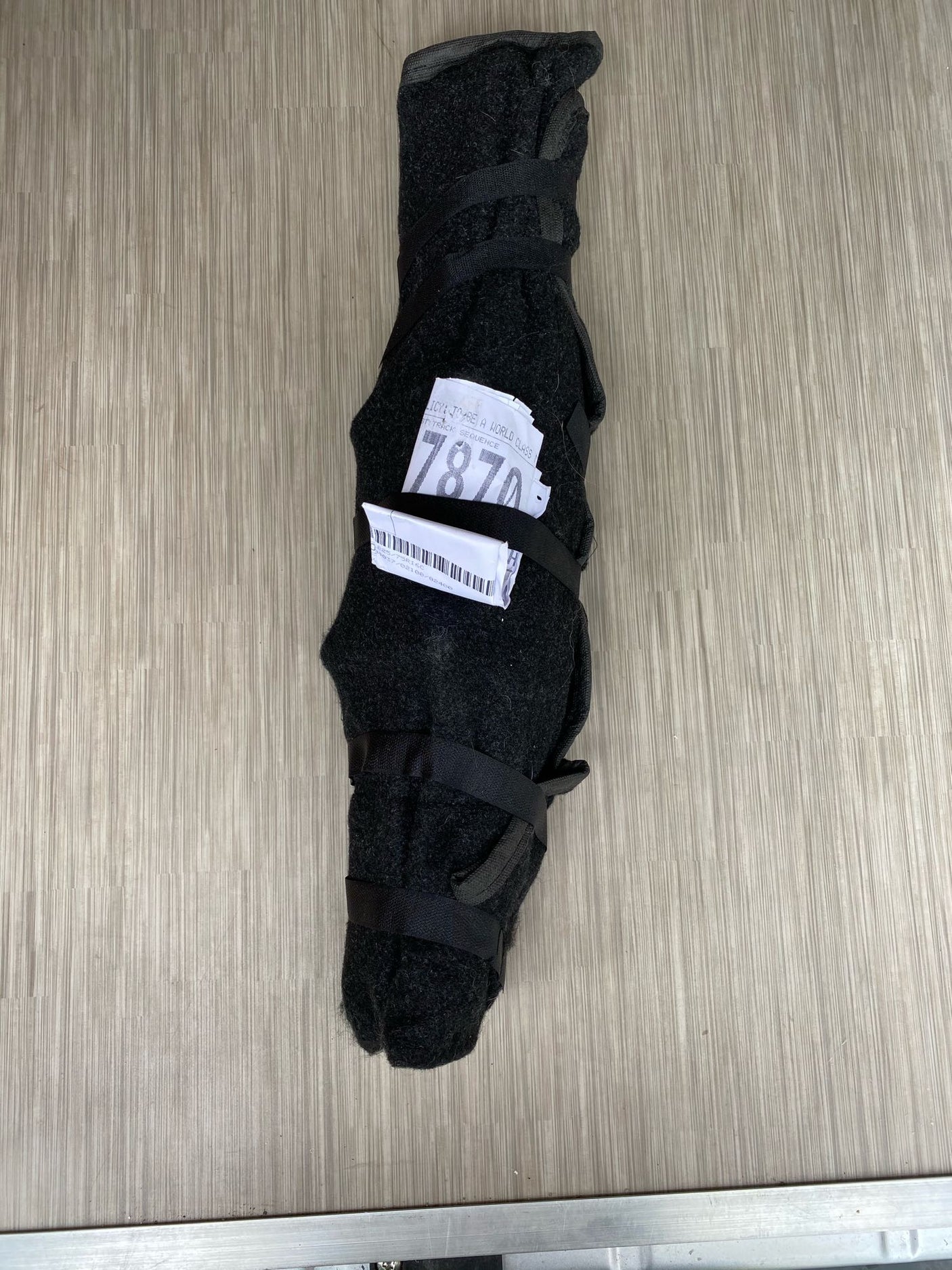 A dark, strapped item with a '7870' label on a wood-grain floor, likely RV rental equipment secured for travel.