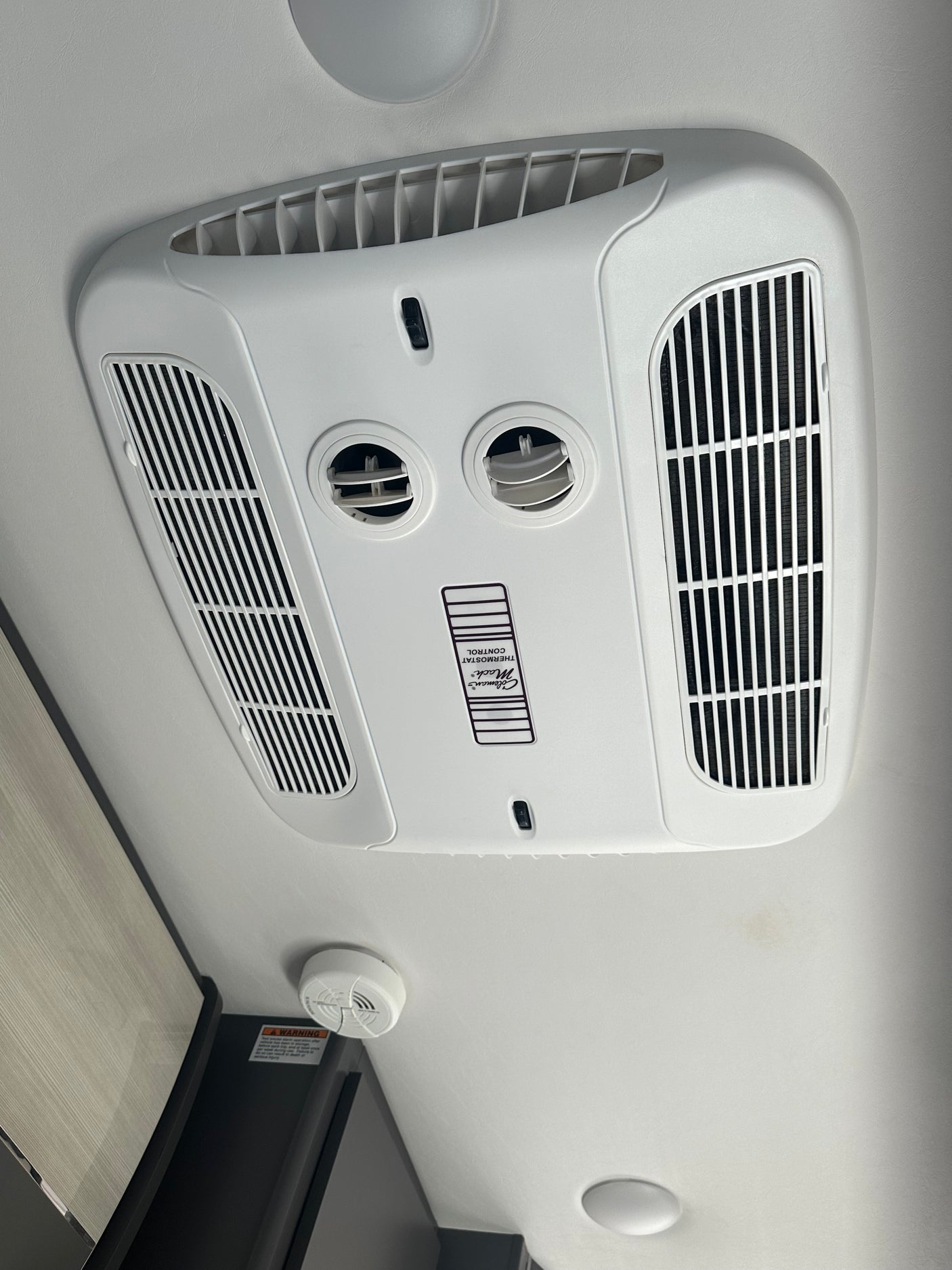RV rental ceiling featuring a white Coleman Mach air conditioner with adjustable vents and a smoke detector.